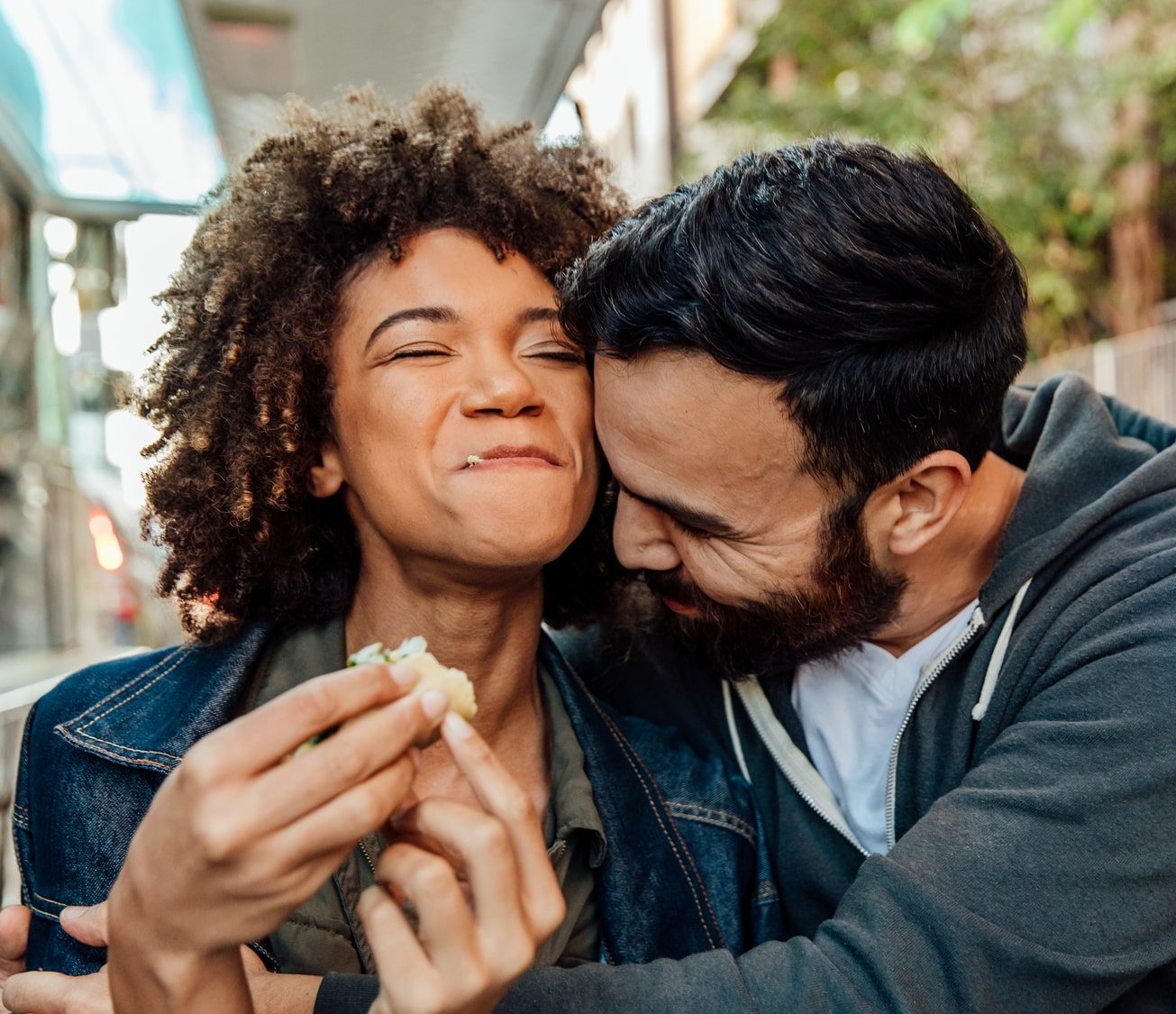 Man Hugging Woman Eating Sandwich